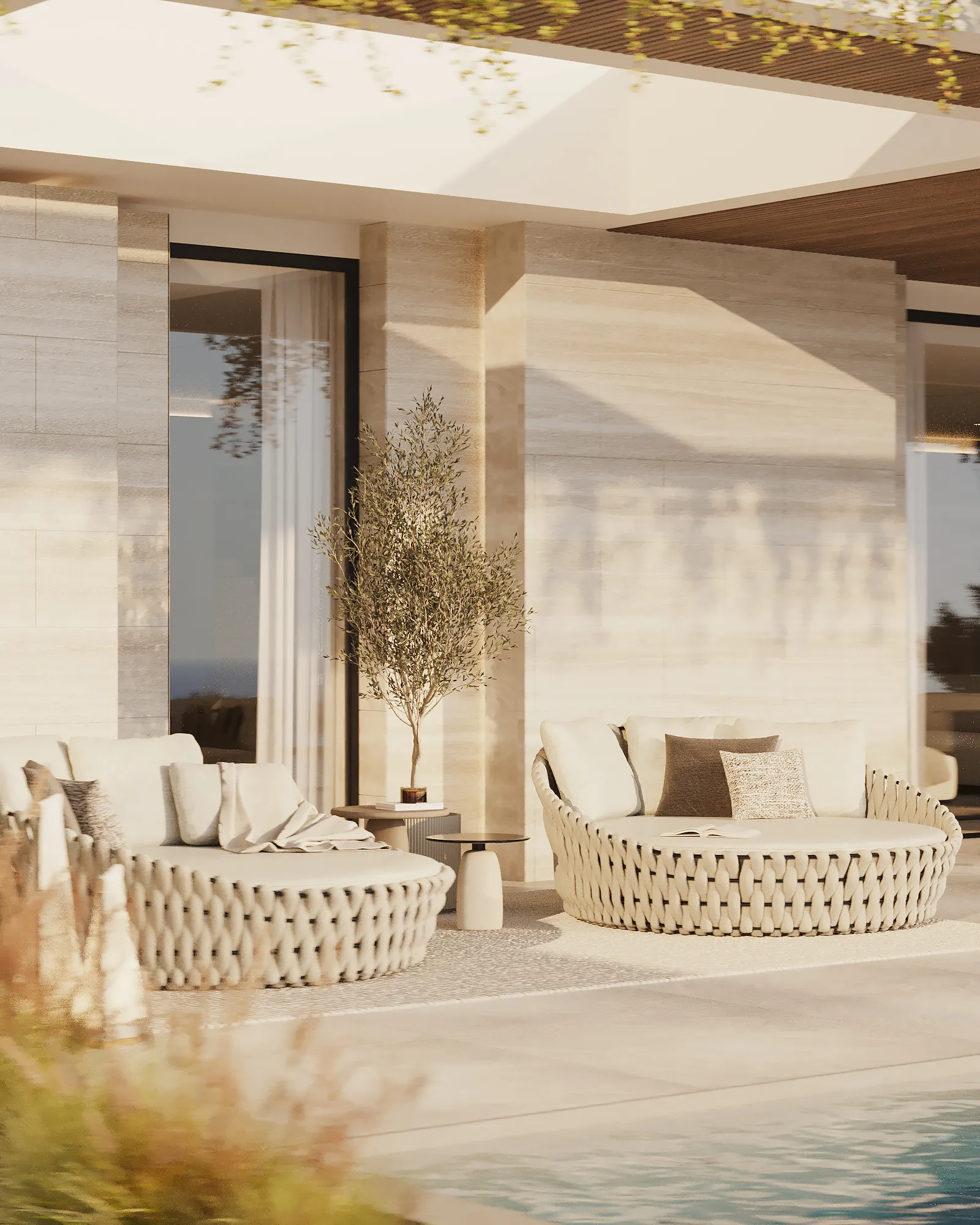 Modern outdoor terrace with two round wicker sofas with cushions beside a swimming pool and a small potted tree.